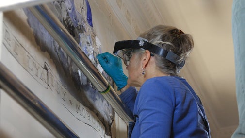 Specialist conservator repairing a section of the frieze painting on the wall at Greenway, Devon